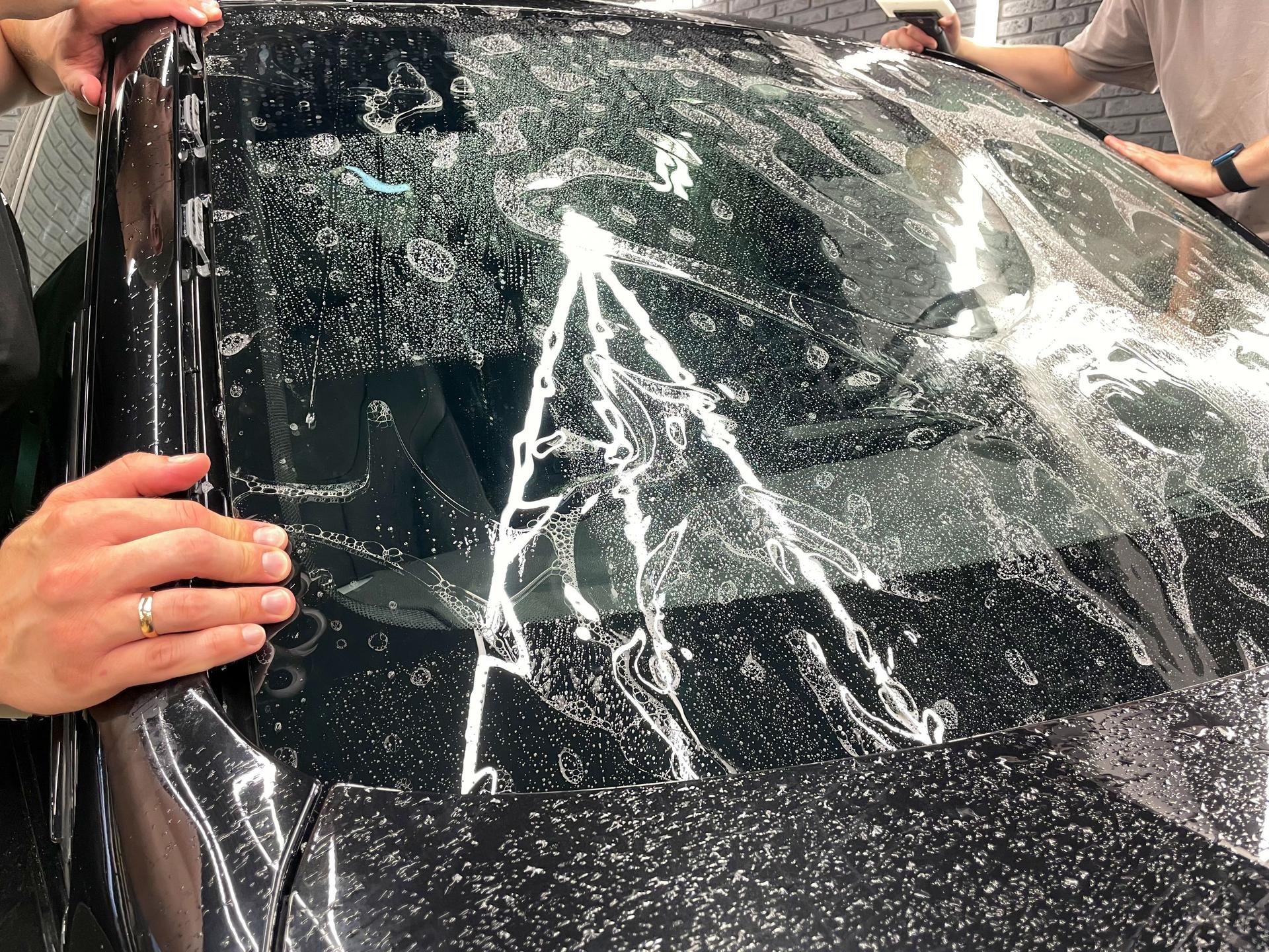 The process of installing the PPF on the windshield of a car.