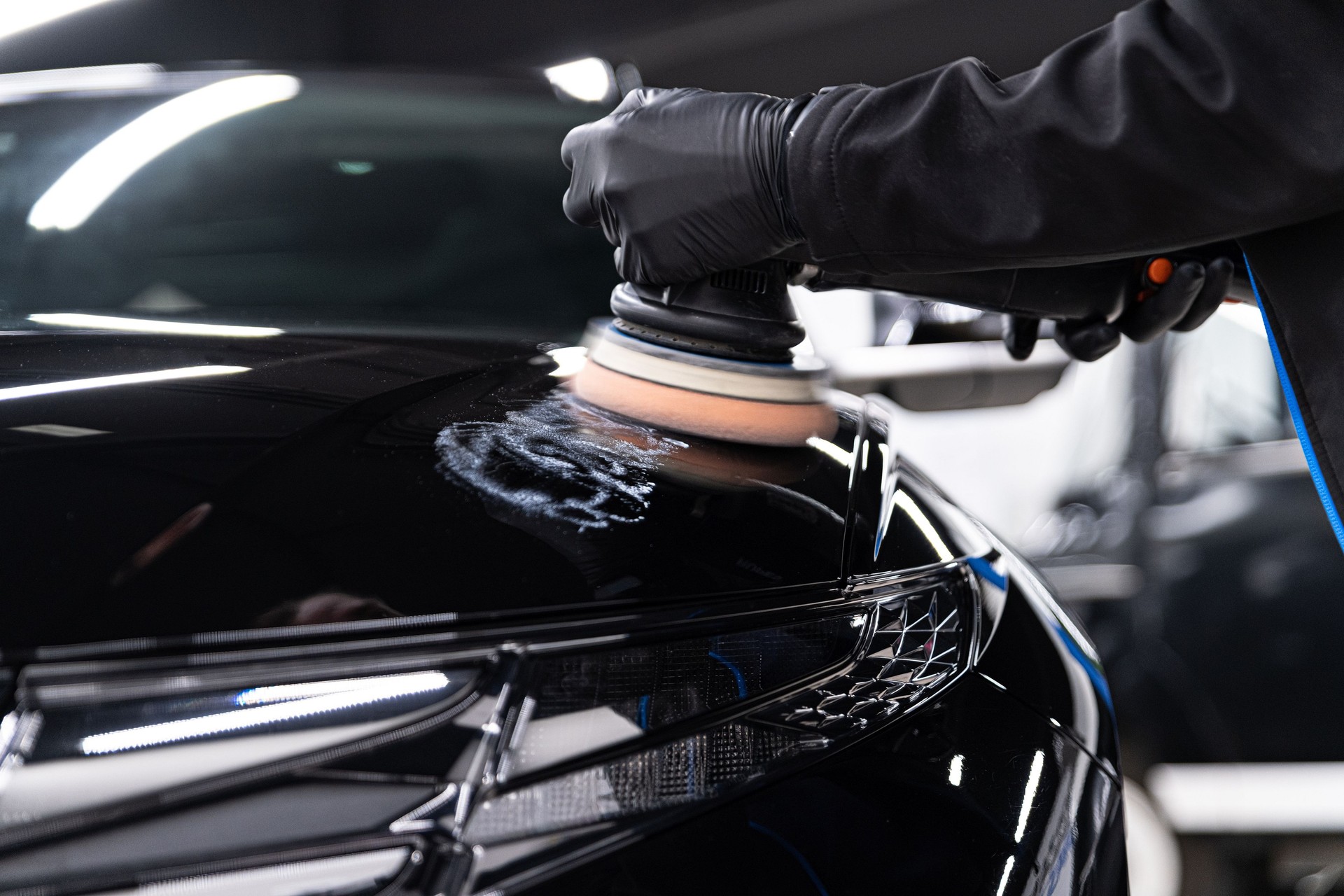 Man worker of car detailing studio removing scratches on car varnish