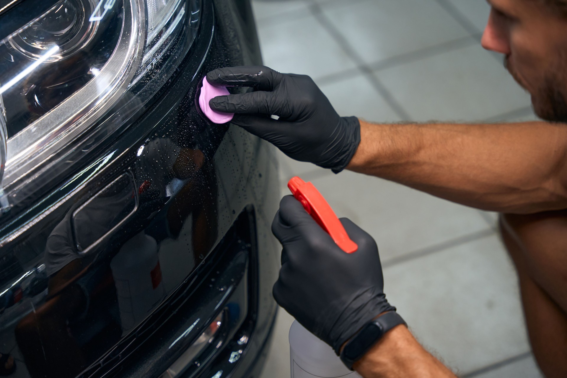 Close up of Detailer is detailing a black car and Clay Bar it