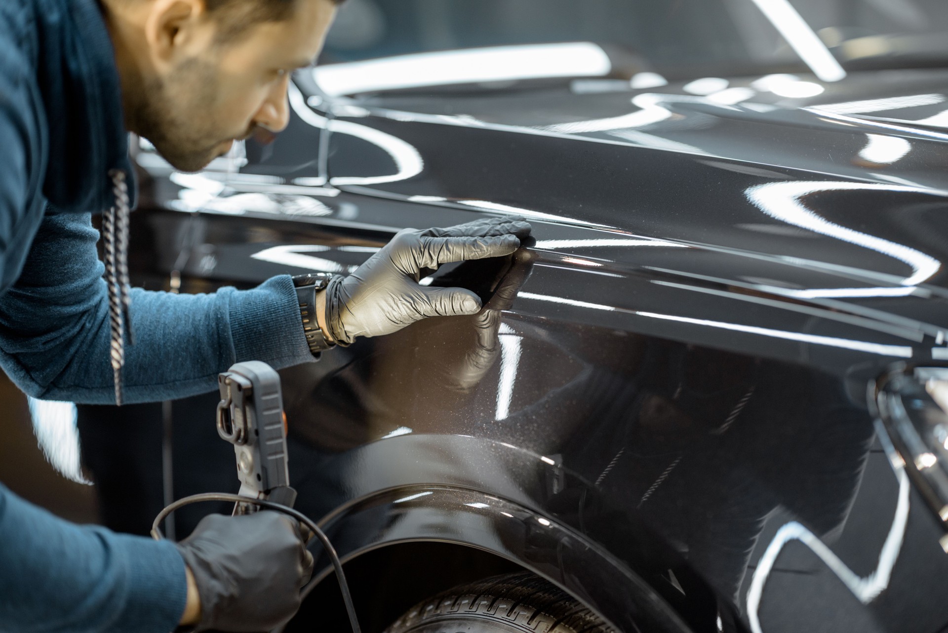 Worker examining vehicle body for scratches