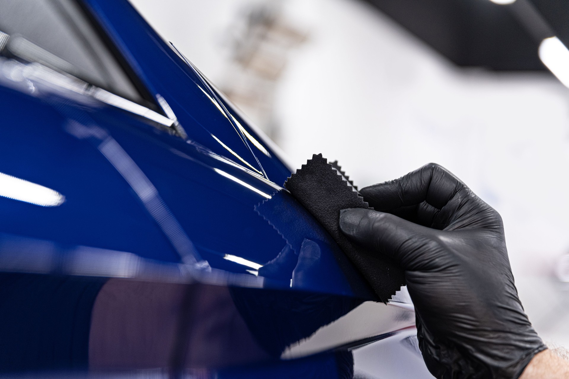 Car detailing studio worker applying ceramic coating on car