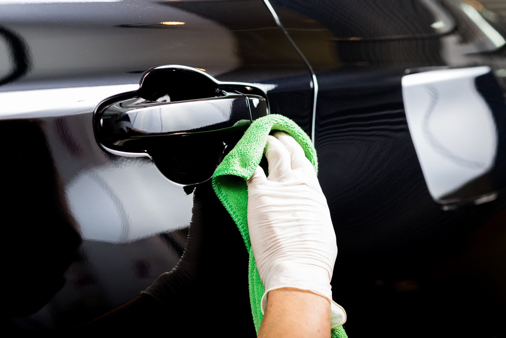 Car detailing series : Worker cleaning black car