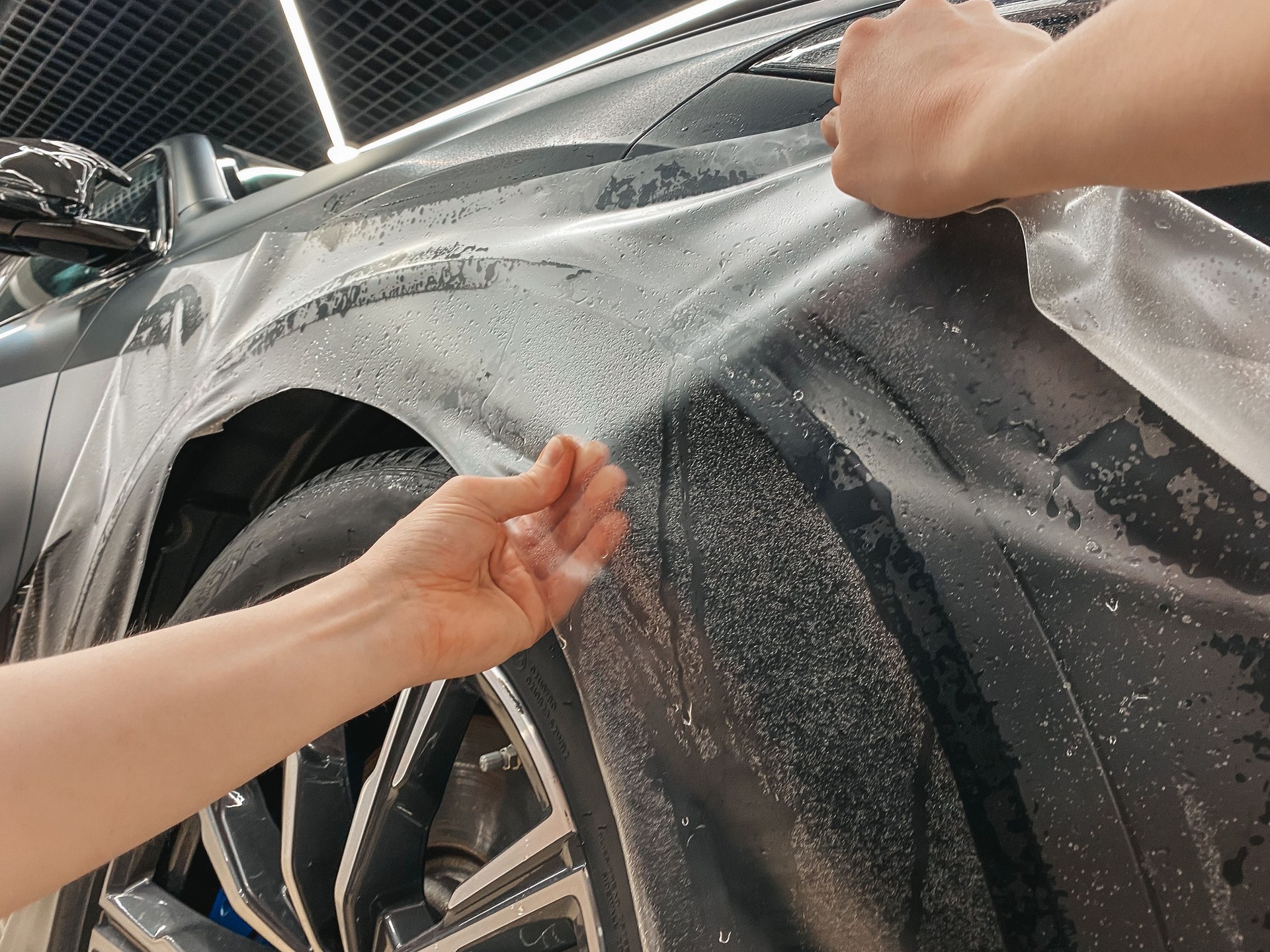 Car wrapping. A car wrapping specialist applies a polyurethane film to the car. Selective focus. PPF protective film against chips and scratches.